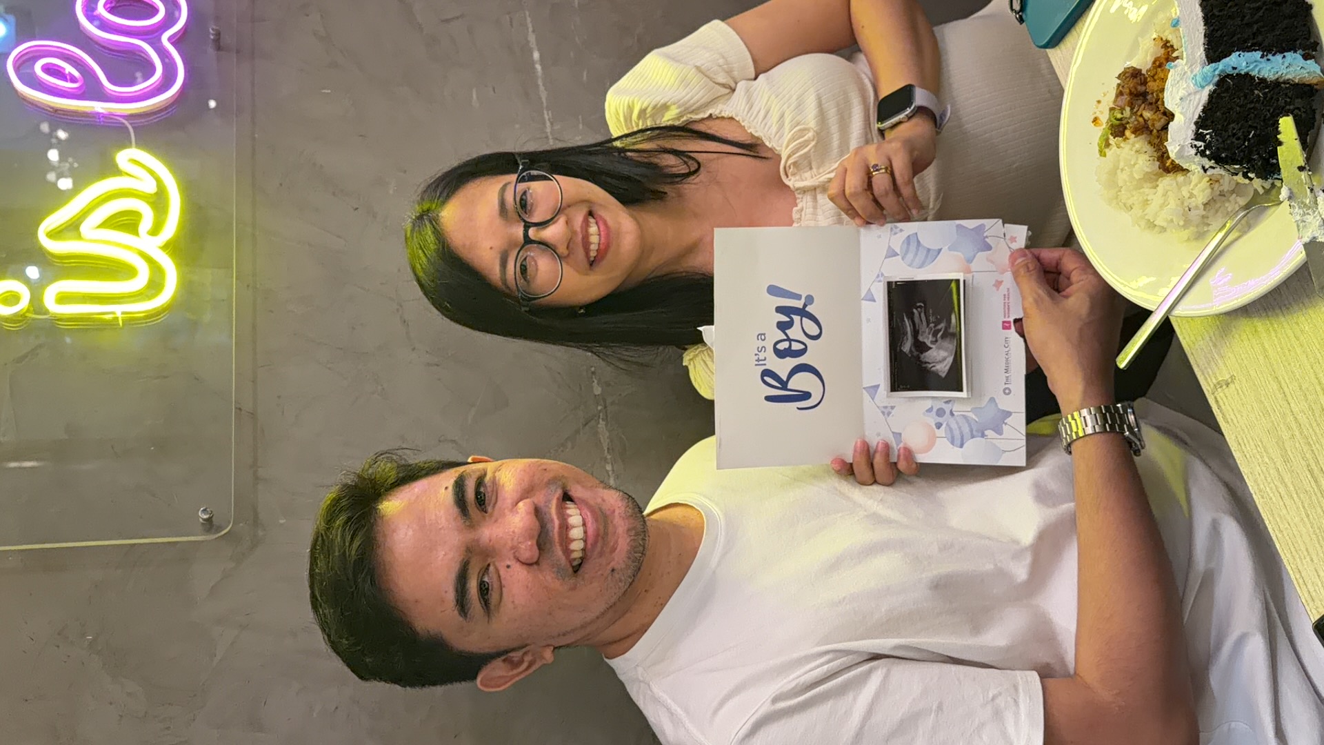Halcyon’s parents smiling and holding their It’s a Boy reveal card